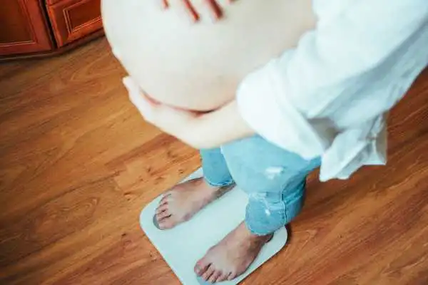 Image of woman weighing herself and experiencing weight gain through pregnancy Pudsey